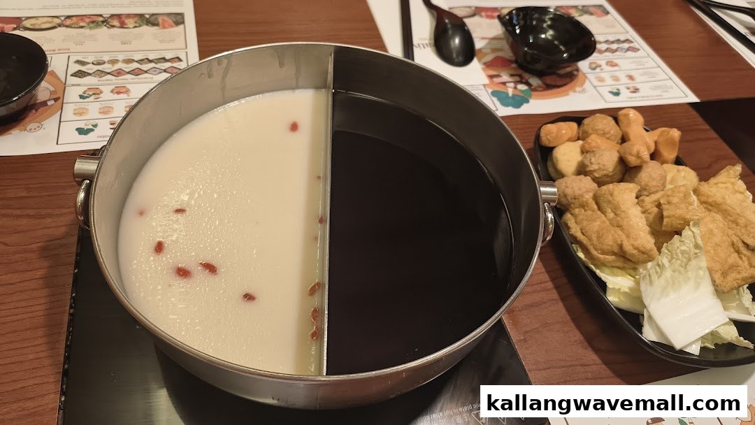 A split hot pot with two broths, accompanied by a plate of shabu-shabu ingredients.