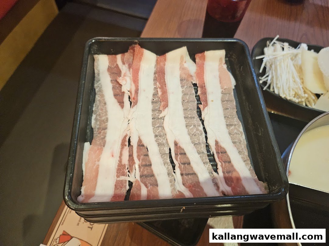 A tray of thinly sliced meat and fresh vegetables for shabu-shabu, ready to be cooked.