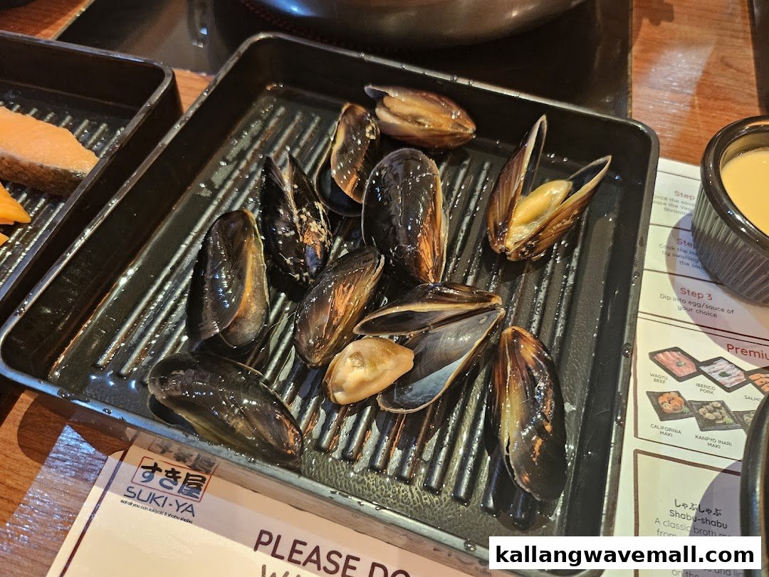 A tray of fresh mussels and salmon on a table, ready for shabu-shabu at Suki-Ya.