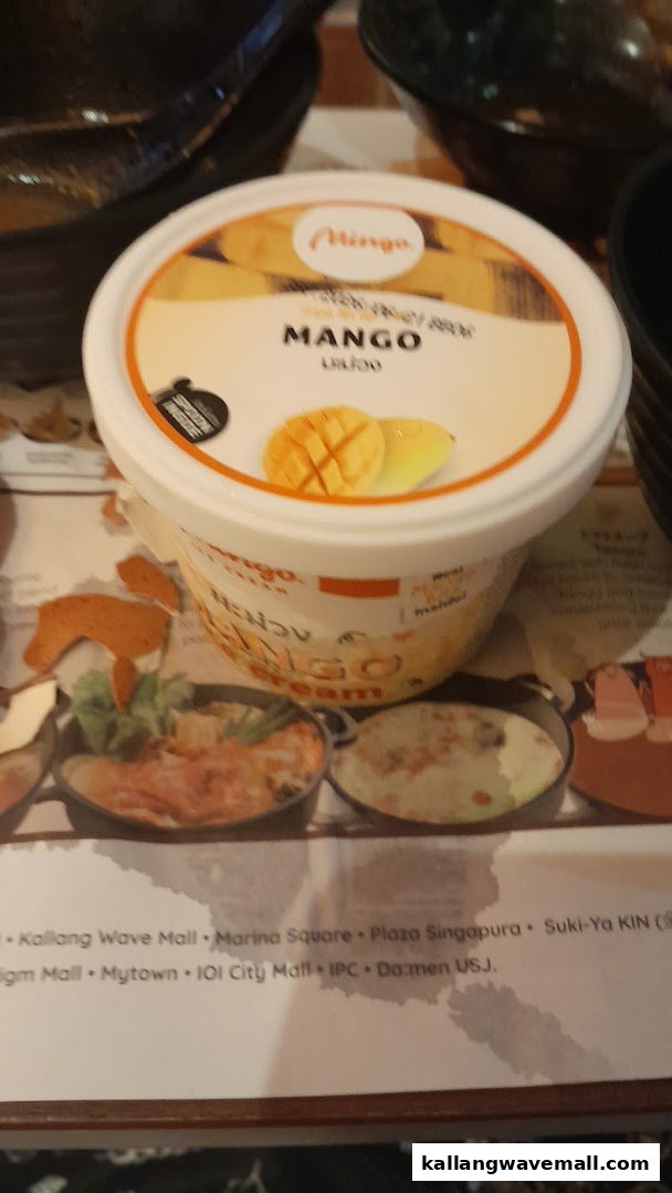 A tub of Mingo Mango ice cream sits on a table with a placemat showing shabu-shabu pots.