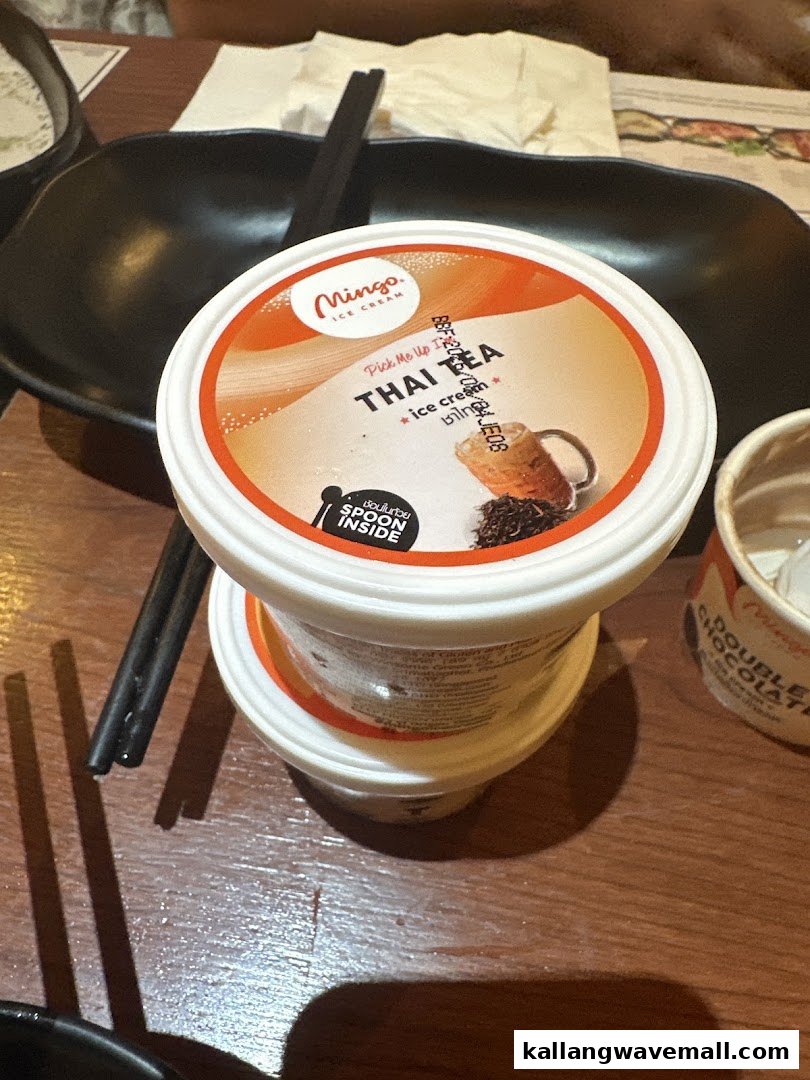 A Mingo Thai Tea ice cream cup on a wooden table, alongside chopsticks and bowls, at Suki-Ya.