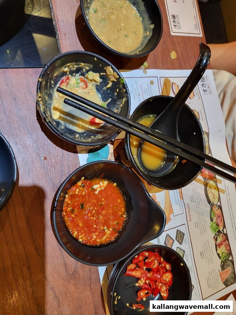 Bowls of various dipping sauces and condiments on a table at a shabu-shabu restaurant.