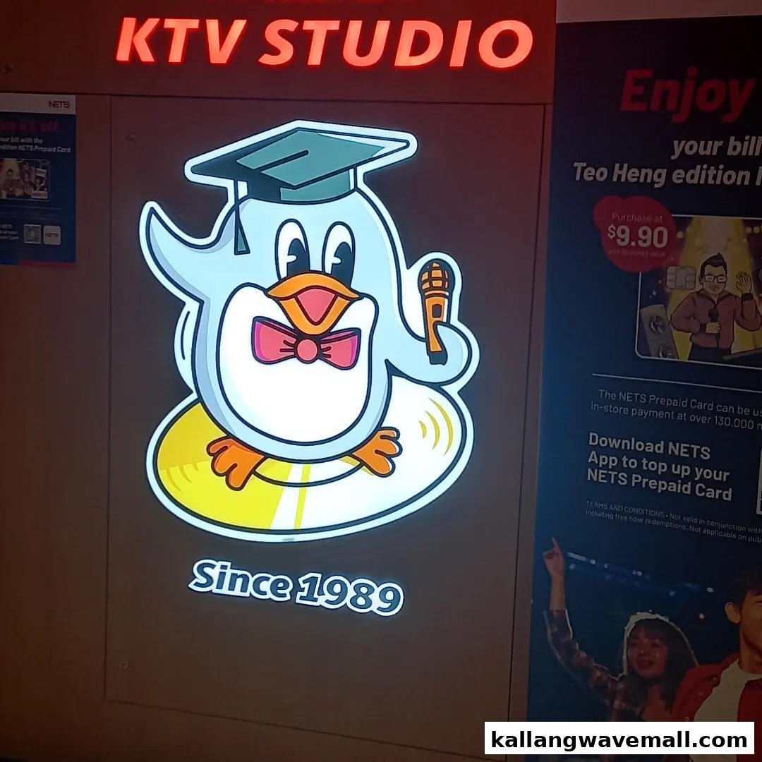 Bright KTV Studio sign with a cute penguin mascot wearing a graduation cap and holding a microphone.