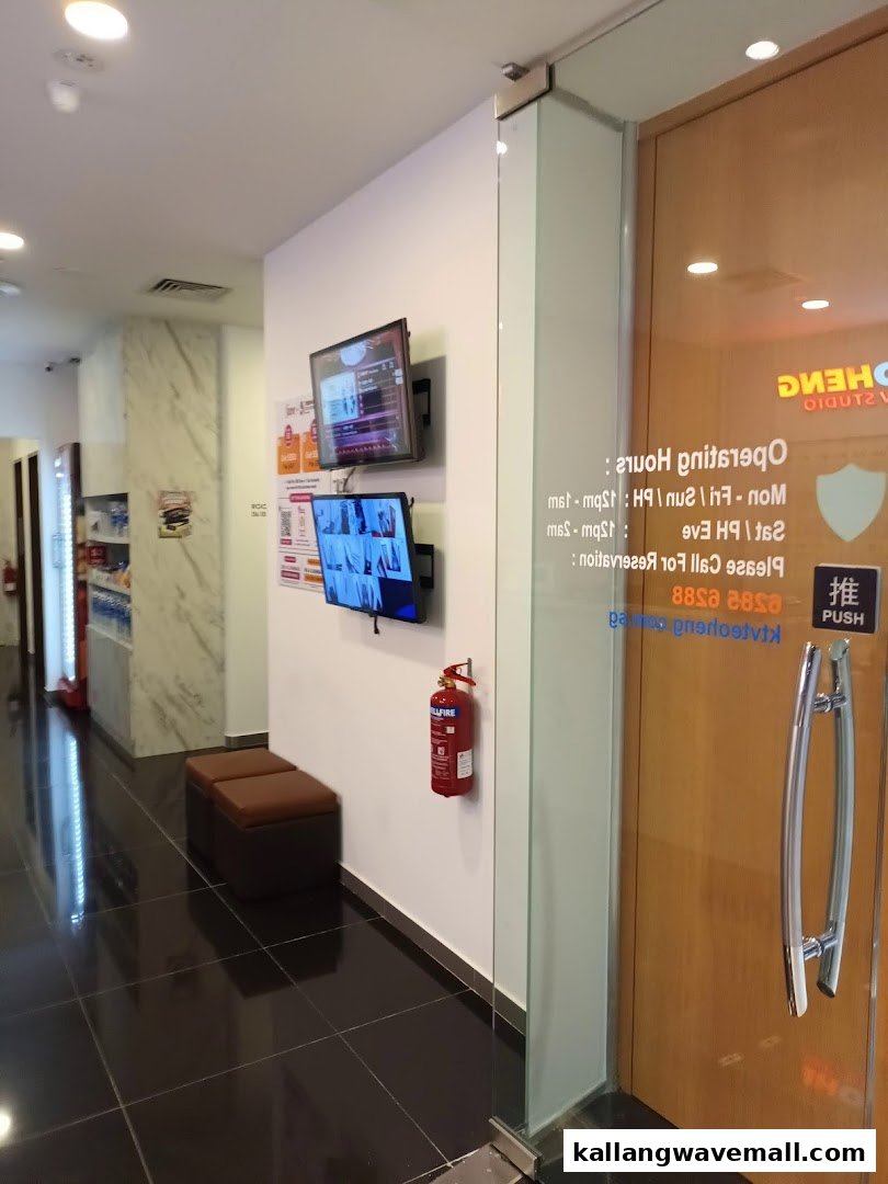 Interior view of a KTV studio hallway with screens, seating, and a glass entrance door.