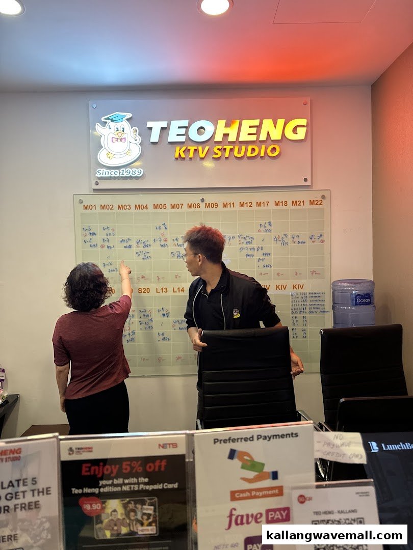 Staff members in a KTV studio office, with a whiteboard and payment options displayed.