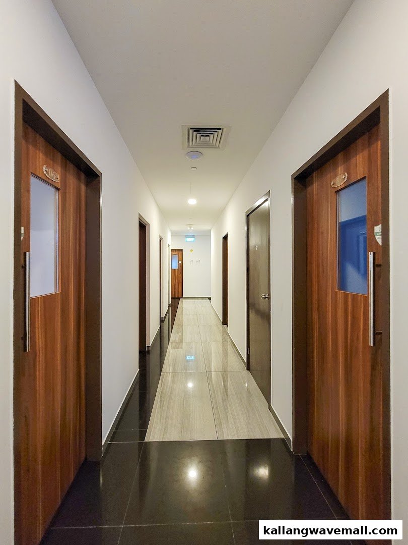 A well-lit hallway with multiple wooden doors leading to private KTV rooms.