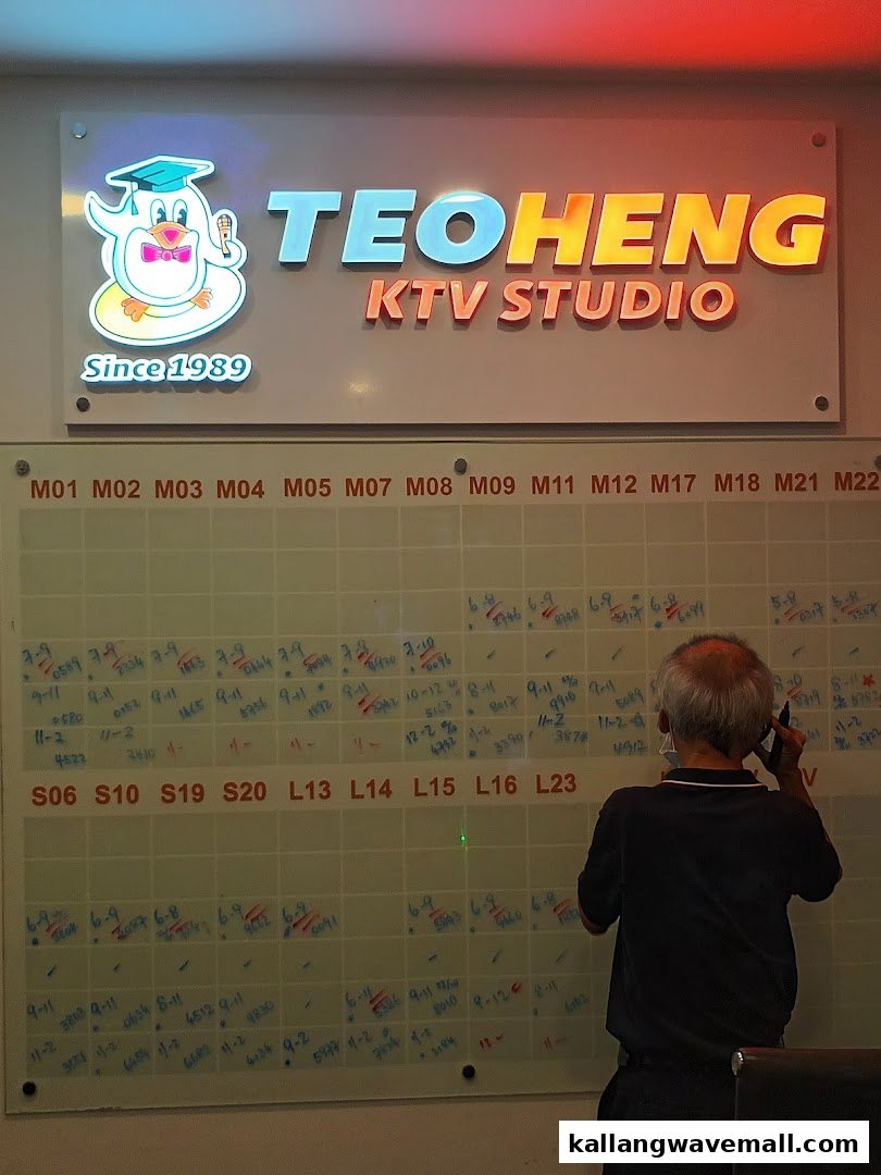 Teo Heng KTV Studio sign and staff member updating a room schedule board.