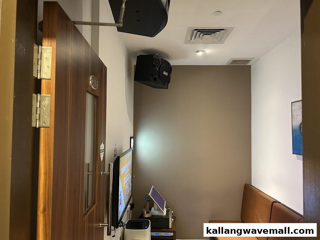 Interior view of a modern KTV room with screen, speakers, and comfortable seating.