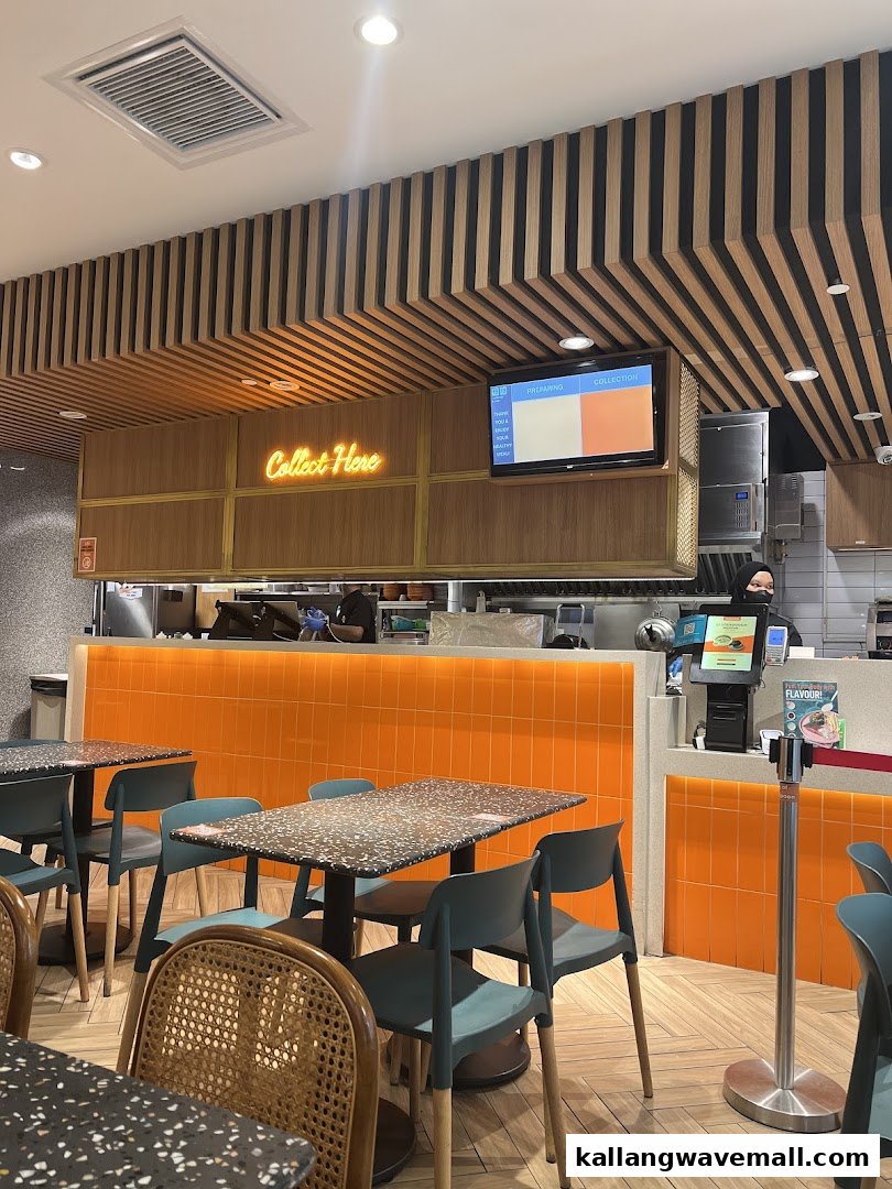 An interior view of The Soup Spoon Union, showing dining tables, a vibrant orange counter, and a 'Collect Here' sign.