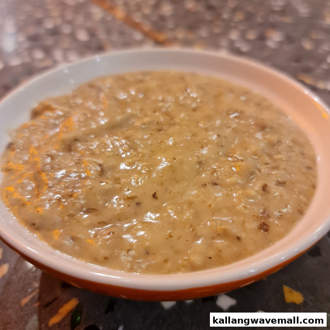 A close-up of a creamy, chunky soup in a white bowl with an orange rim.