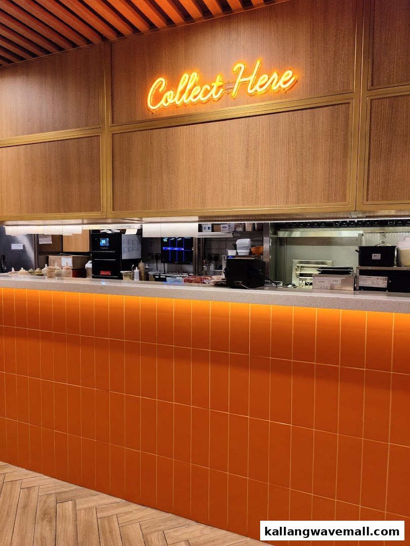 An interior view of The Soup Spoon Union's vibrant orange collection counter with a neon 'Collect Here' sign.