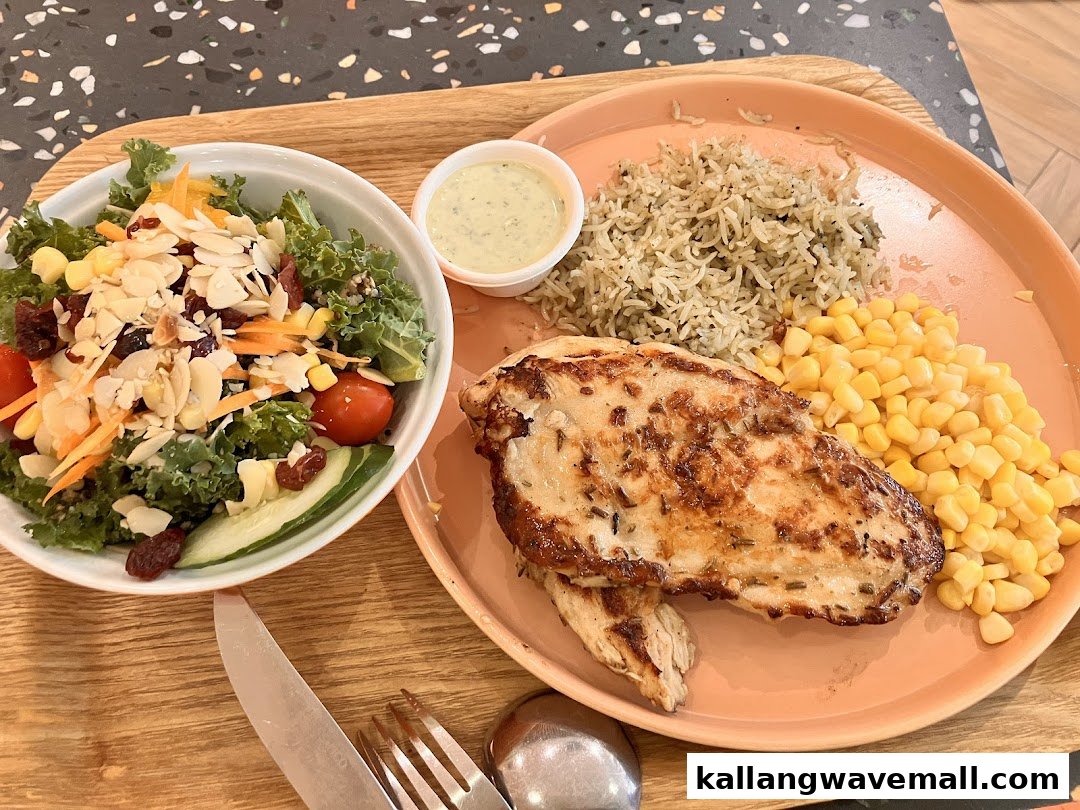 A healthy meal featuring grilled chicken, rice, corn, and a vibrant salad with dressing.