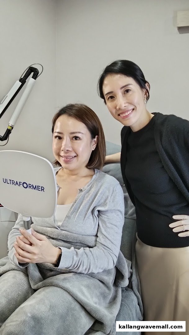 A client smiles while holding a mirror, accompanied by a smiling staff member at Venusia Medical Aesthetics Clinic.