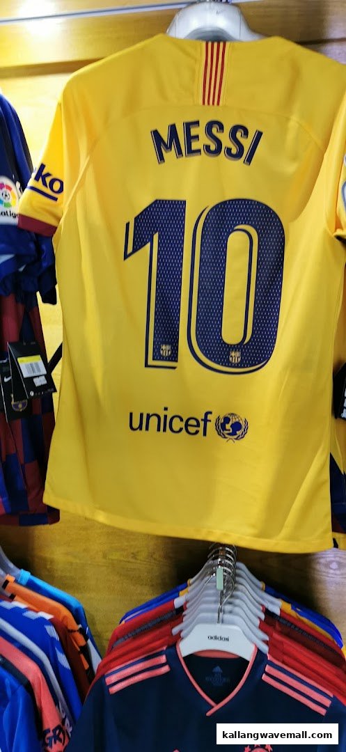 A vibrant yellow football jersey with 'MESSI' and '10' on the back, displayed in a sports apparel shop.