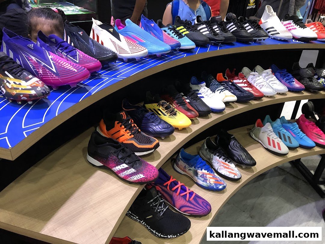 A vibrant display of various athletic shoes, including football boots, arranged on curved shelves in a retail store.