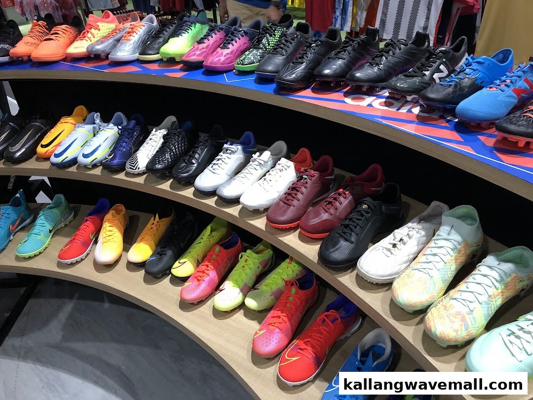 A vibrant display of various sports cleats and athletic footwear arranged on curved shelves in a retail store.