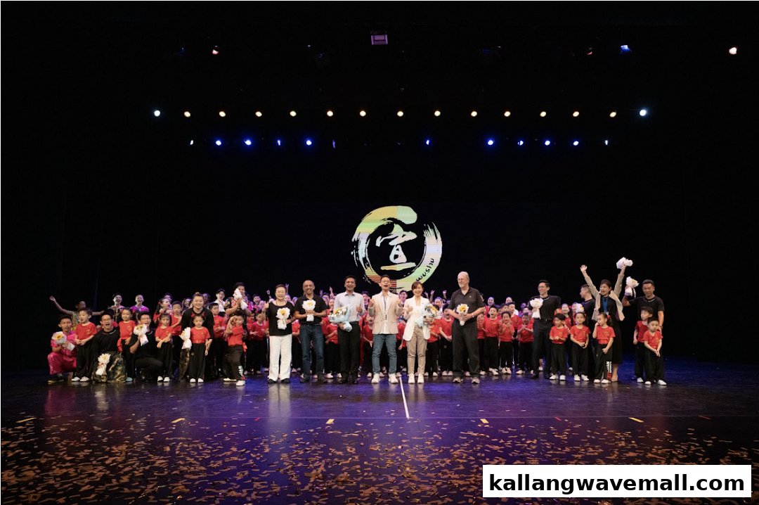 A large group of Xuan Sports students and instructors celebrate on stage after a Wushu performance.