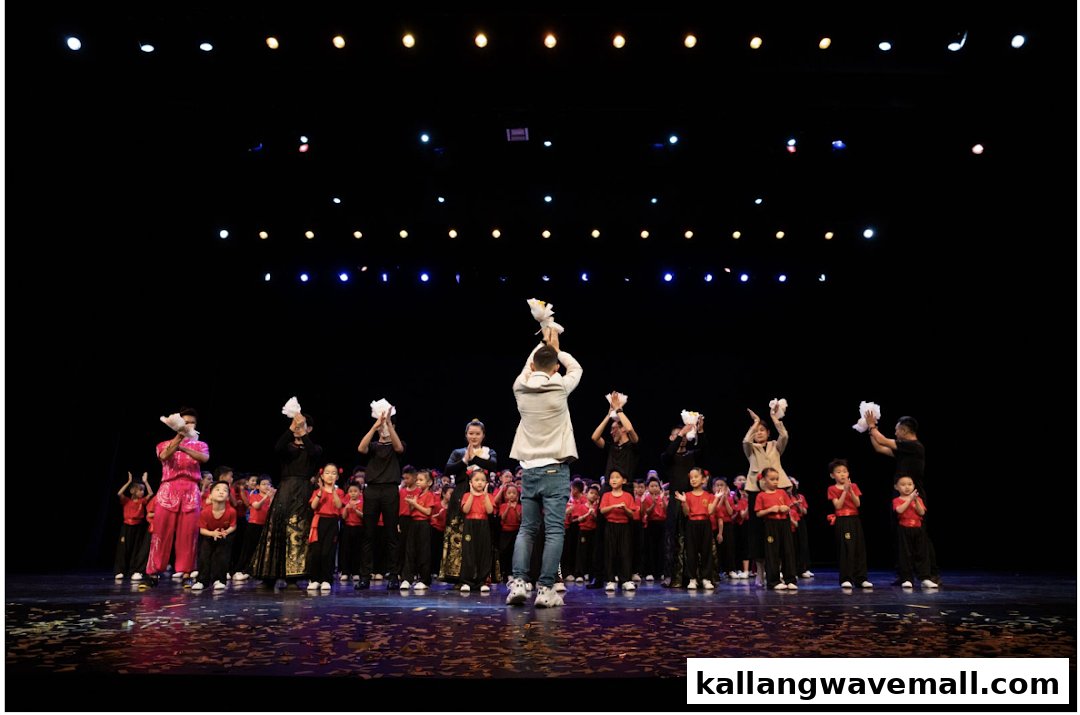 A group of performers, including children and adults, on a stage, some holding bouquets, after a show.