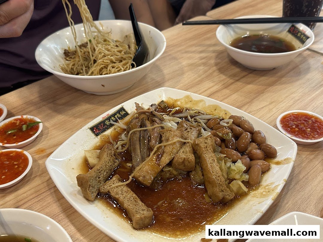 A delicious plate of braised duck, peanuts, and tofu with noodles and chili sauce on a wooden table.
