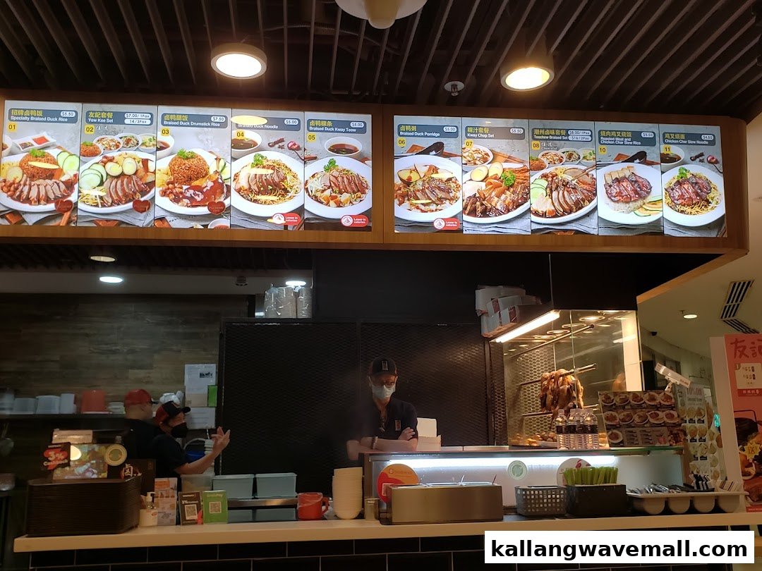 A food stall counter featuring large digital menu boards displaying various duck and chicken dishes with prices.