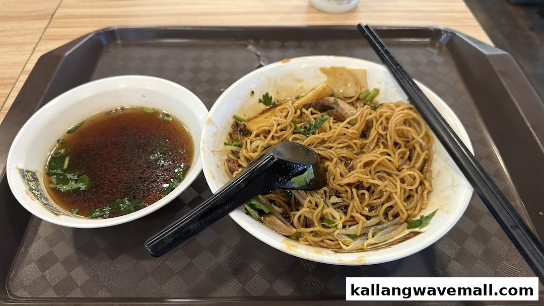 A delicious bowl of dry noodles with a side of clear soup on a serving tray.