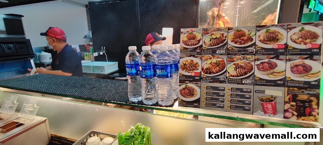 A staff member prepares food behind a counter with a large menu display featuring various duck and chicken dishes.