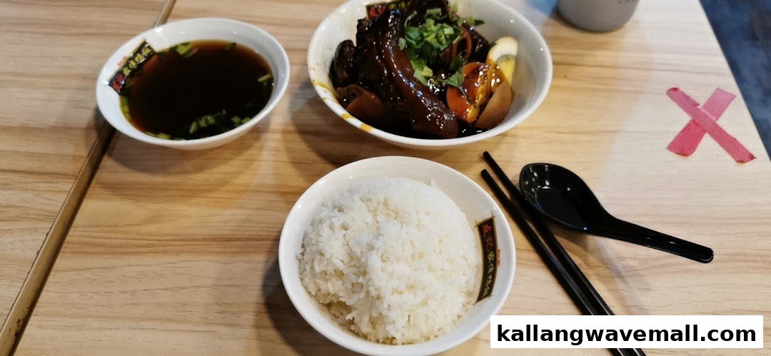 A delicious meal featuring braised meat, rice, and a bowl of soup on a wooden table.