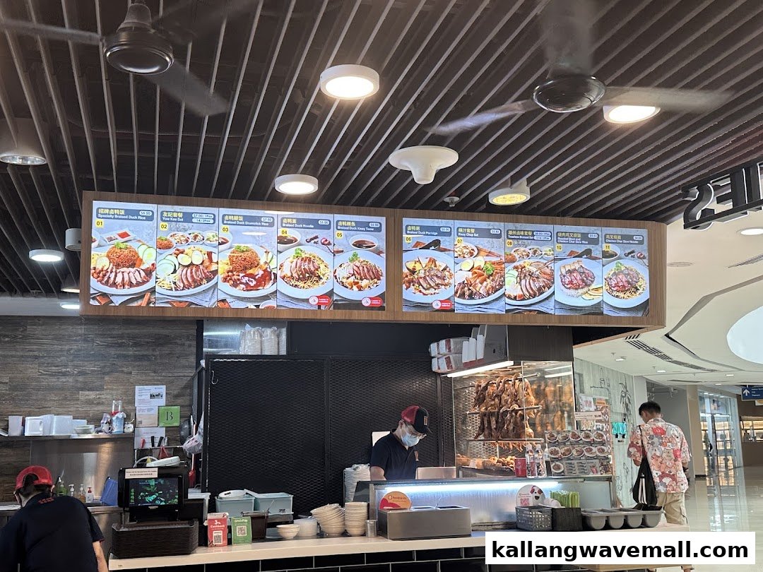 A digital menu board at Yew Kee Specialities displaying various braised duck, roasted pork, and chicken dishes.