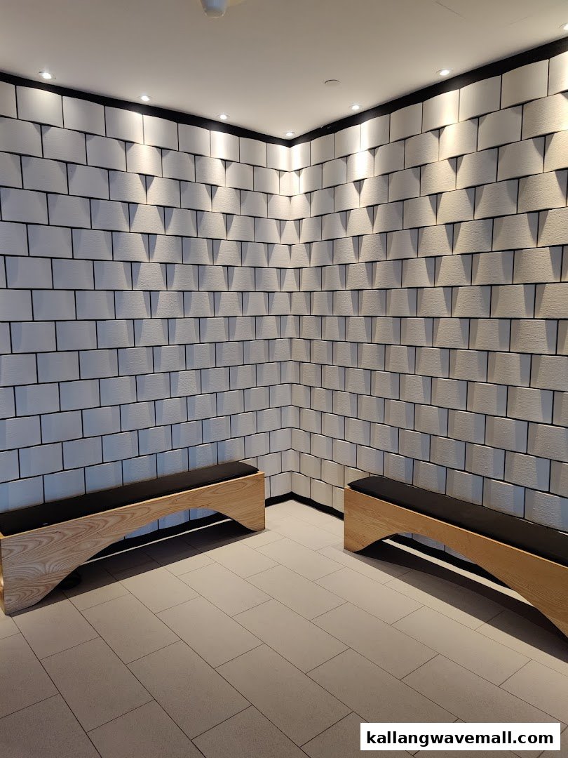 A modern waiting area inside Yunomori Onsen Spa, featuring textured white walls, recessed lighting, and wooden benches.