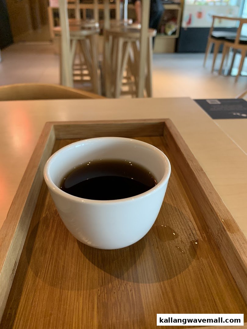 A warm beverage in a white cup on a wooden tray, set on a table in a relaxing spa lounge.