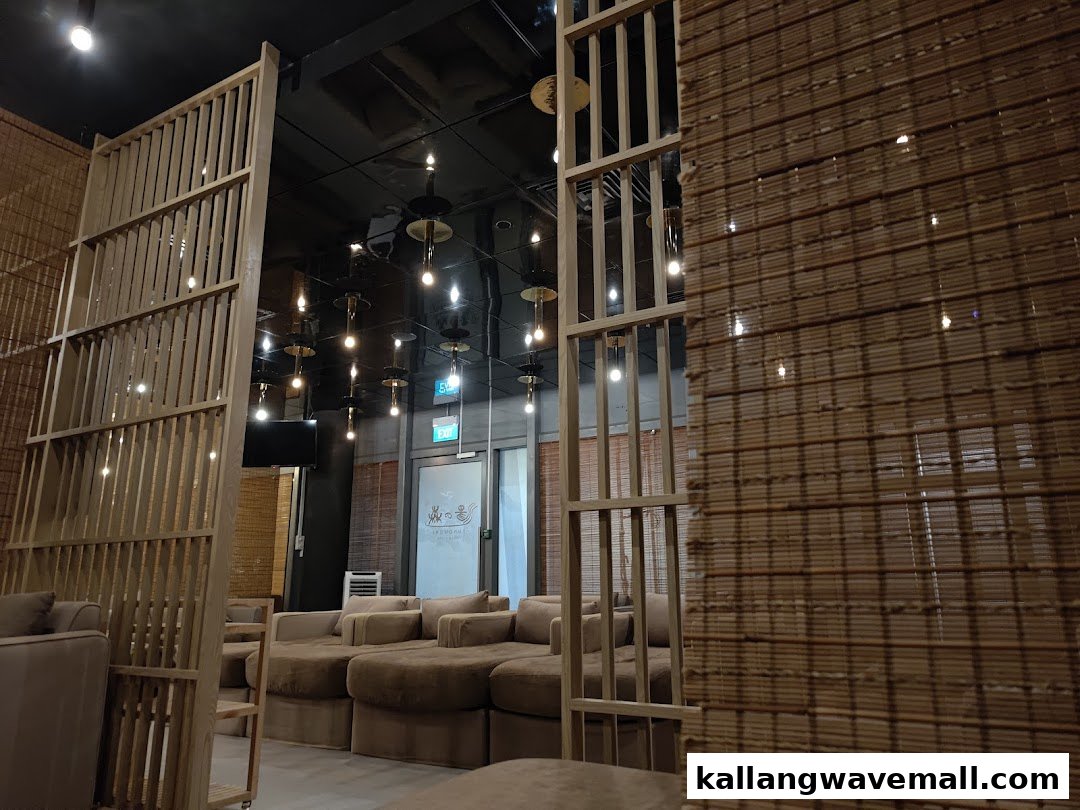 A cozy lounge area with comfortable sofas and warm lighting, featuring bamboo-style partitions.