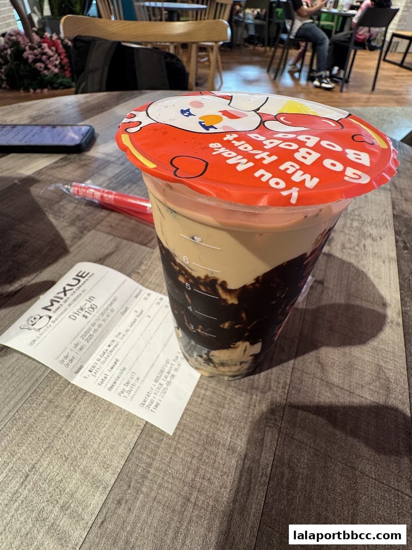 A cup of MIXUE boba drink with a receipt on a wooden table.