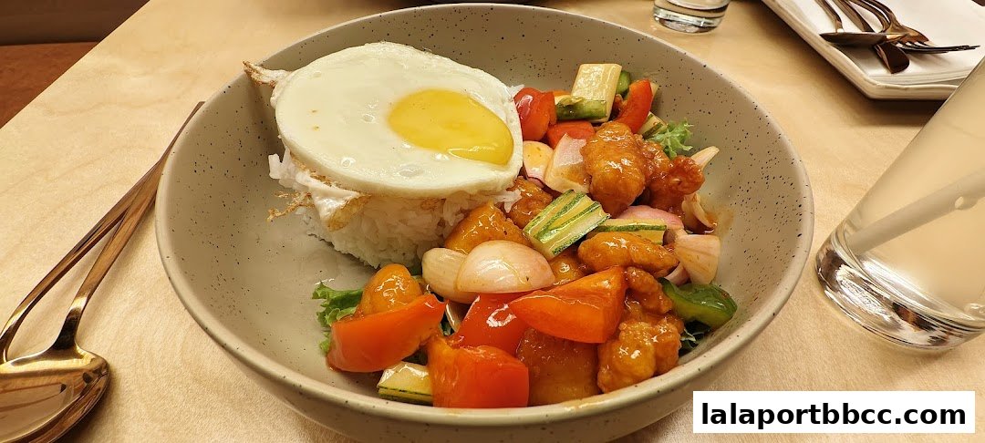 A close-up of a delicious meal featuring rice, a fried egg, and stir-fried vegetables with chicken.