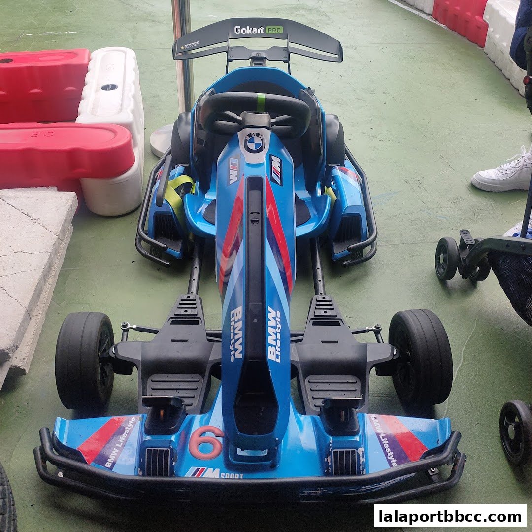 A blue electric go-kart with BMW branding and a spoiler, ready for racing.