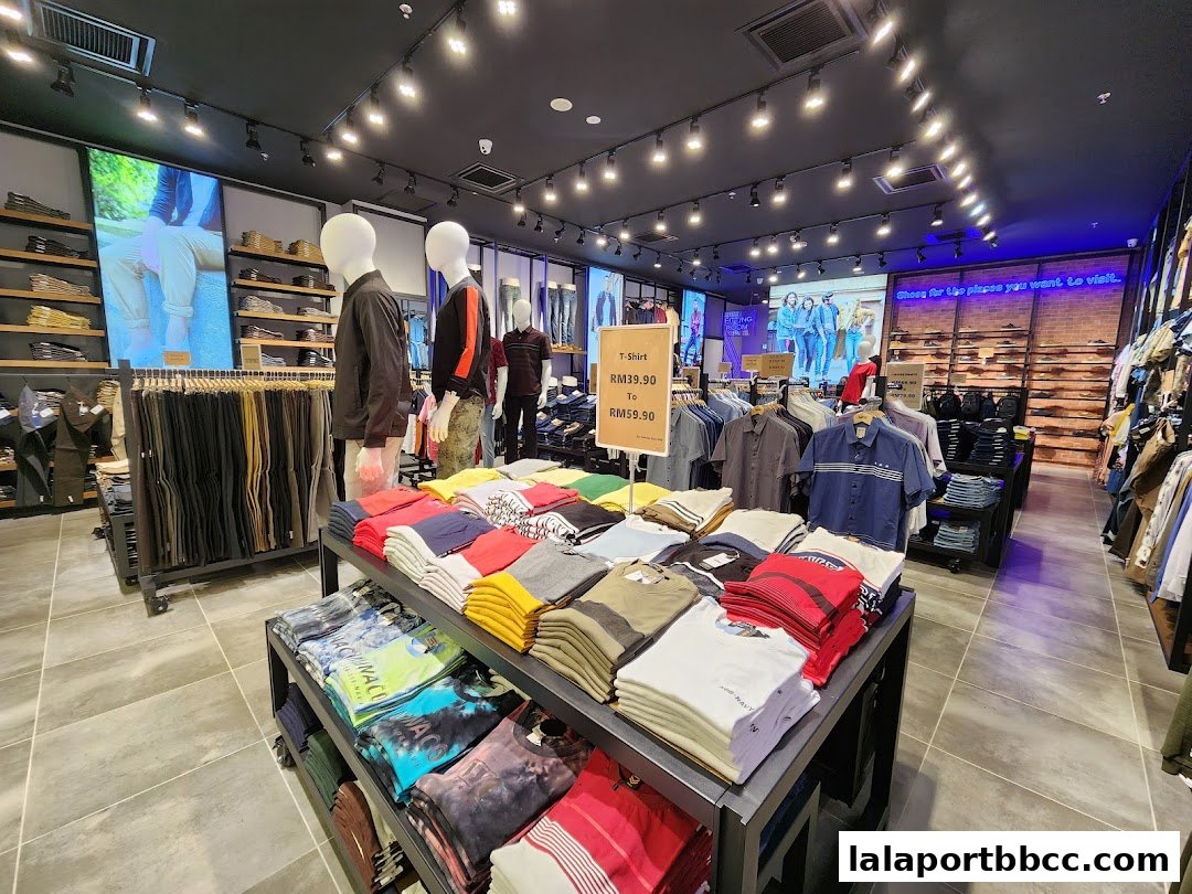 Interior view of a clothing store showcasing folded t-shirts, mannequins, and apparel displays.