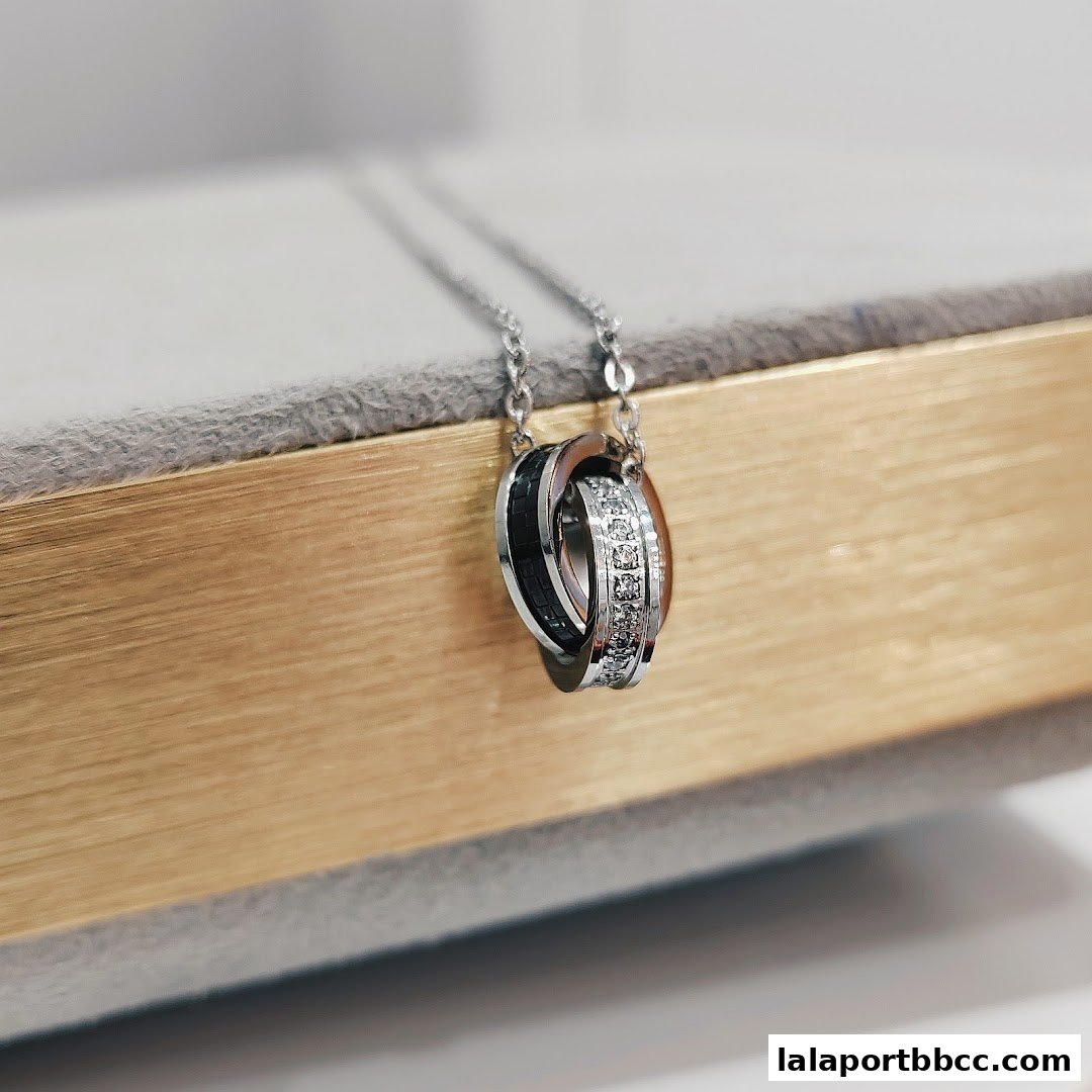A close-up shot of a silver necklace with interlocking rings, one adorned with diamonds.