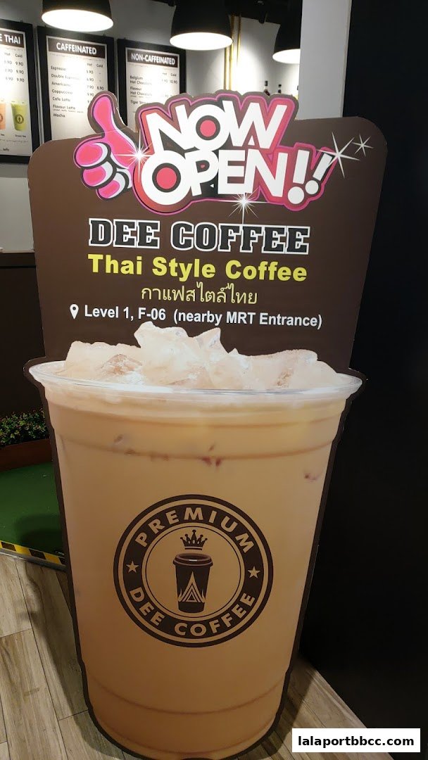 A large cutout of an iced coffee drink with 'Dee Coffee' branding and 'Now Open!' signage.
