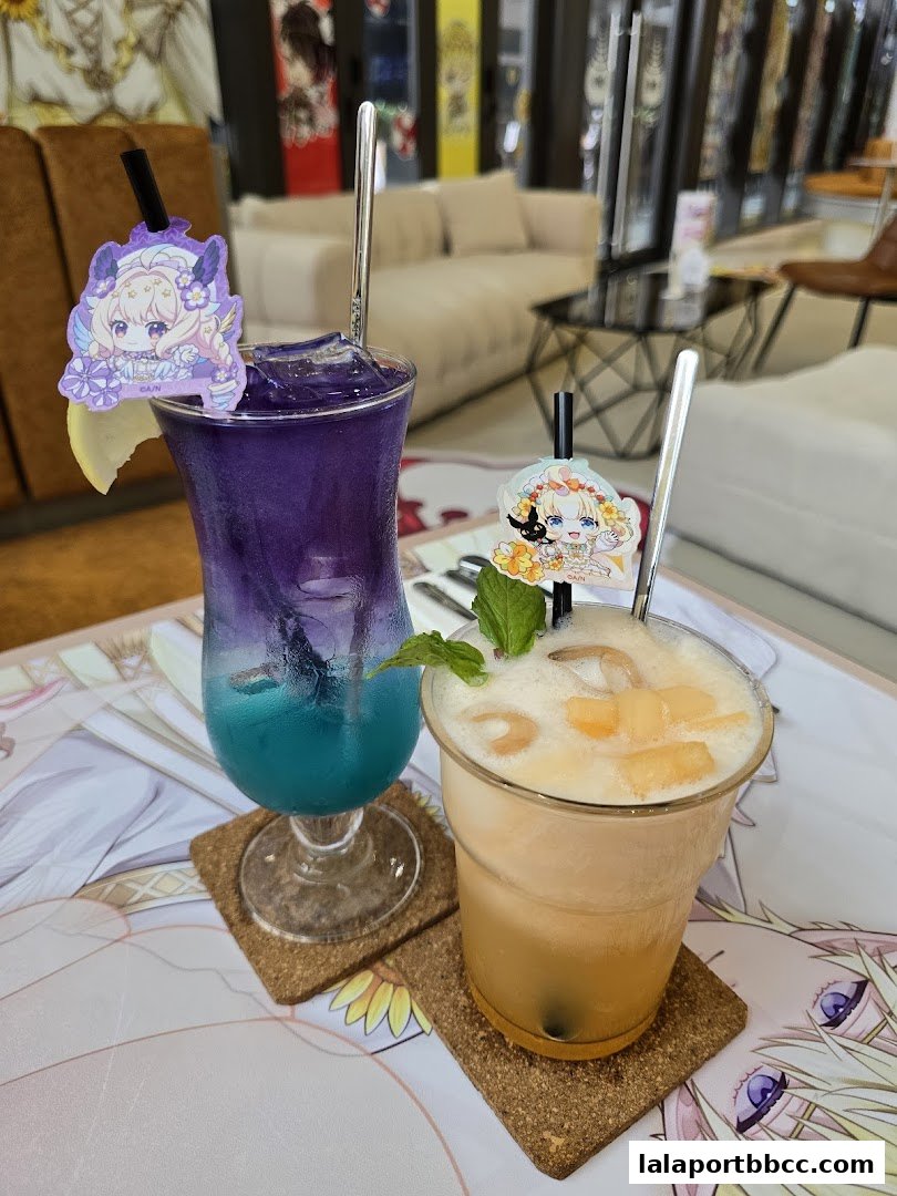 Two colorful drinks with anime-themed toppers sit on a table with decorative mats.