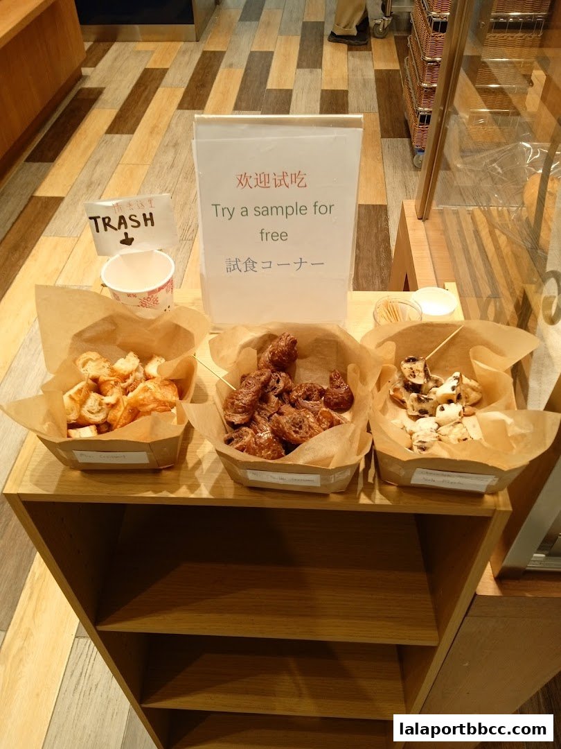 A free sample station with three types of baked goods and a trash bin.