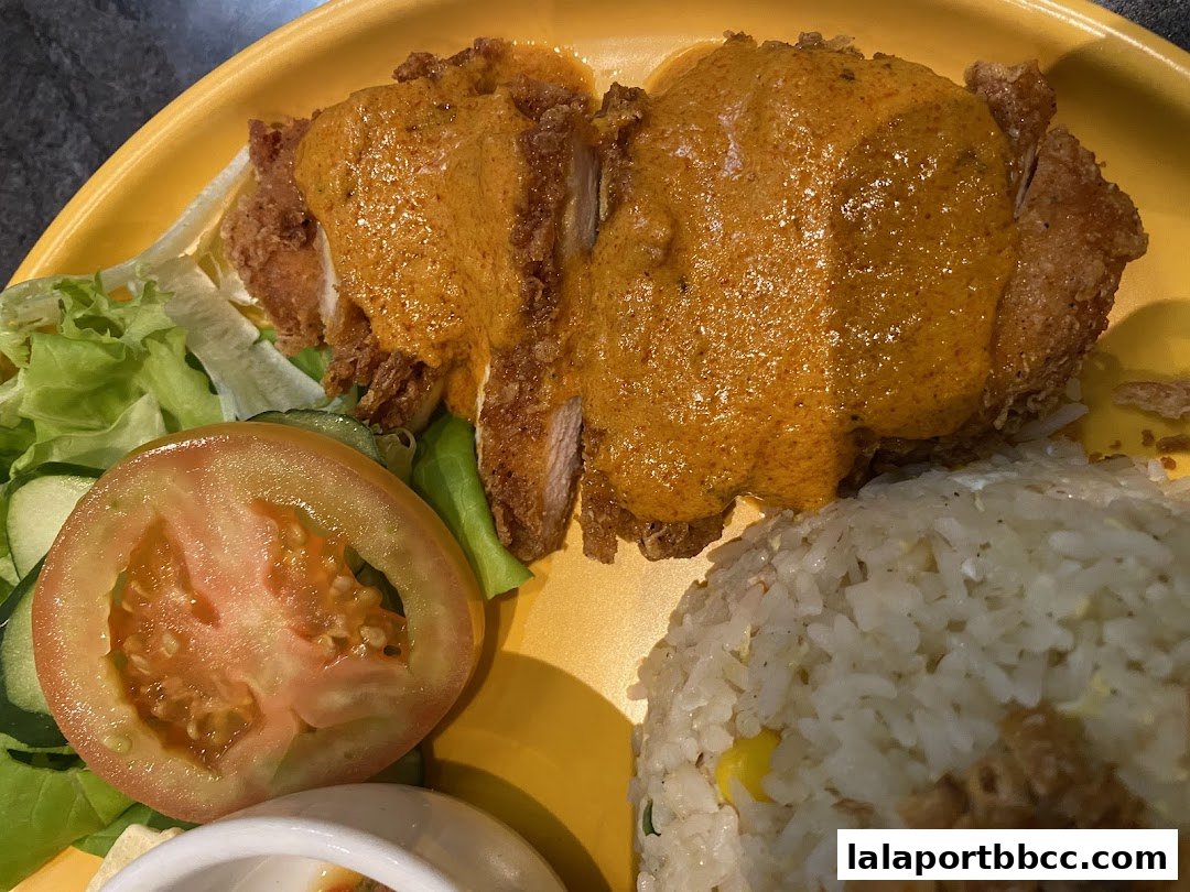 A close-up of a delicious meal featuring fried chicken with sauce, rice, and a side salad.