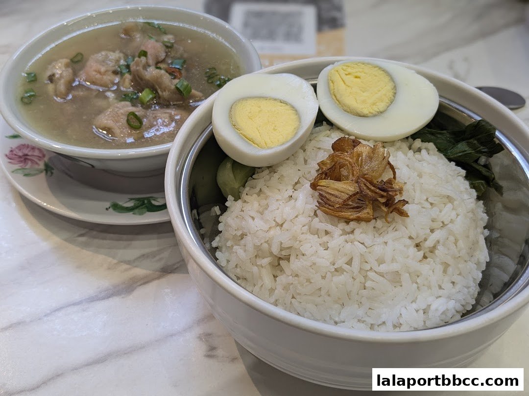 A close-up of a delicious meal featuring rice, boiled eggs, and a bowl of soup.