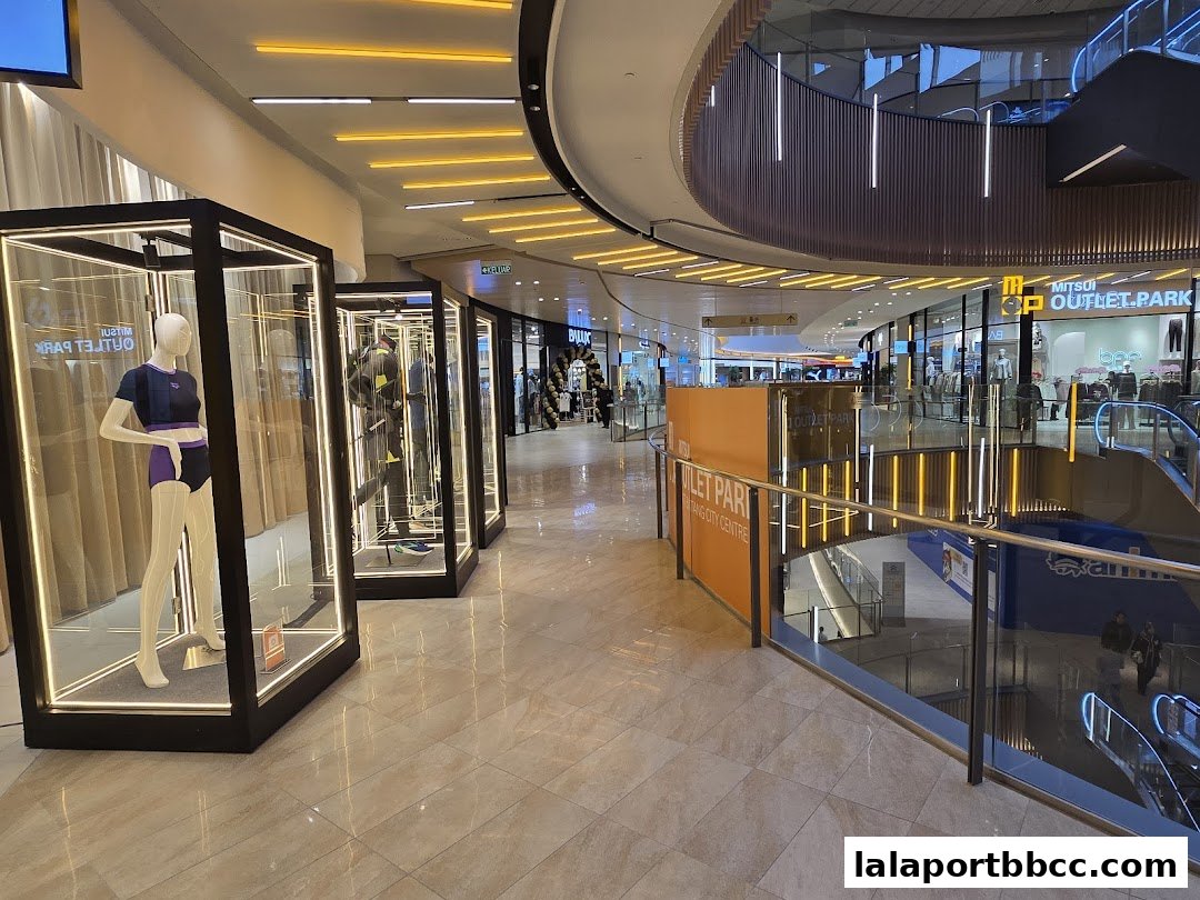 Modern shopping mall interior with display mannequins and escalators.