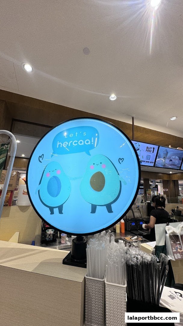 A circular sign with cartoon avocados and the text 'let's hercaa!' hangs above a counter.