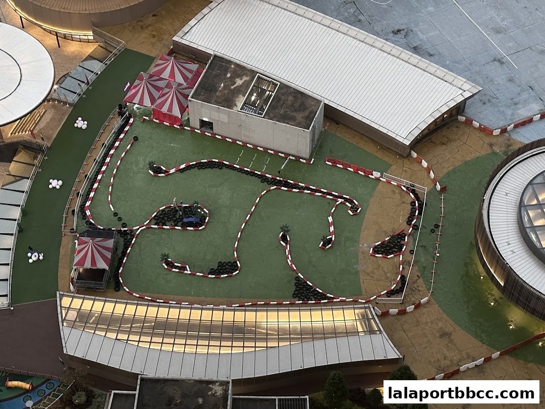 Aerial view of an outdoor go-kart raceway with a winding track and surrounding buildings.