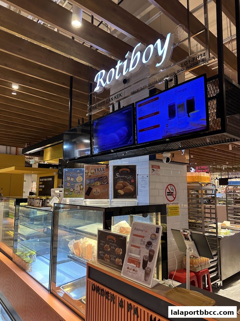 The interior of a Roti Boy bakery with a display counter and illuminated signage.