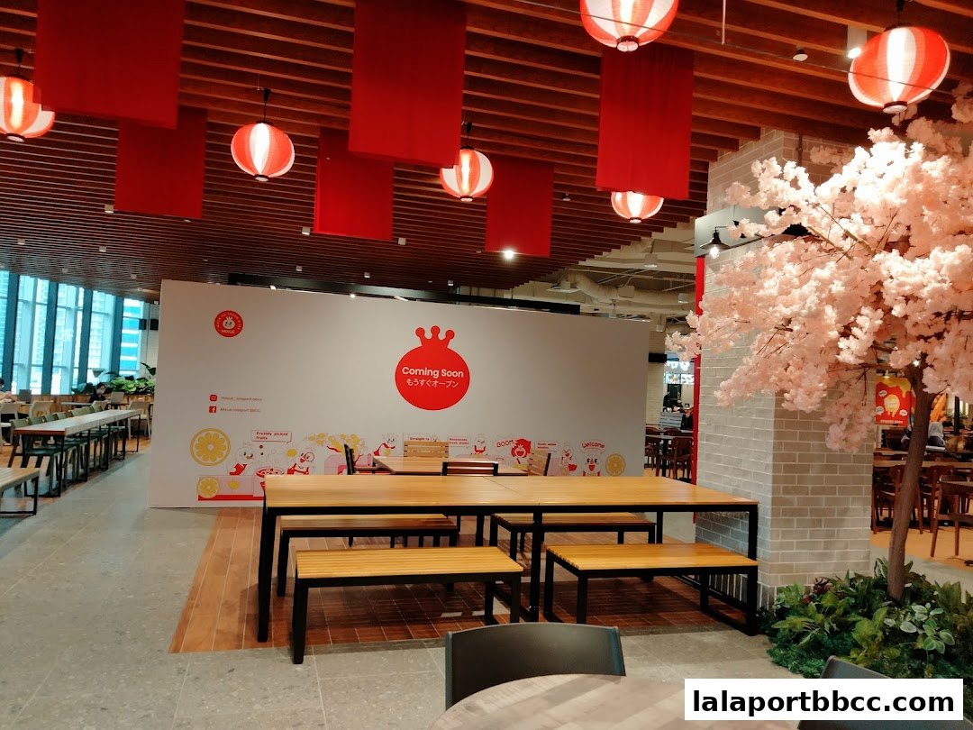 A 'Coming Soon' sign for MIXUE with seating and a decorative cherry blossom tree.
