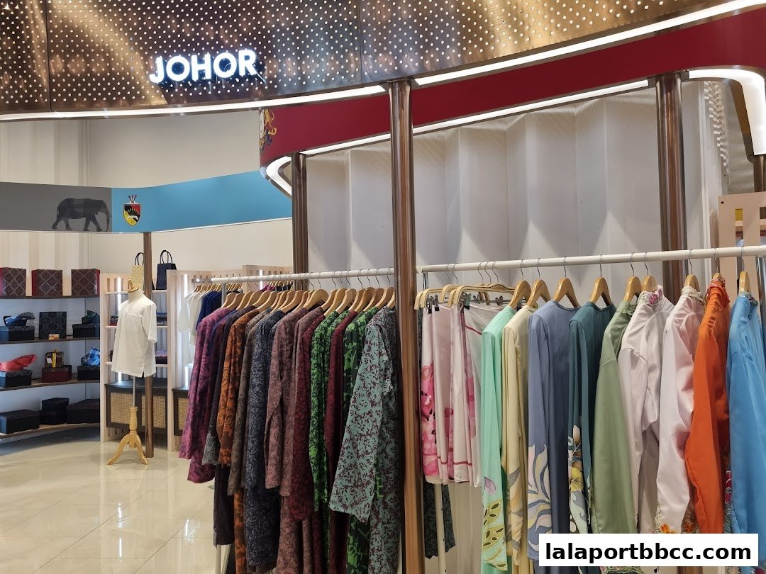 A retail shop interior displaying a variety of colorful traditional Malaysian clothing on hangers.