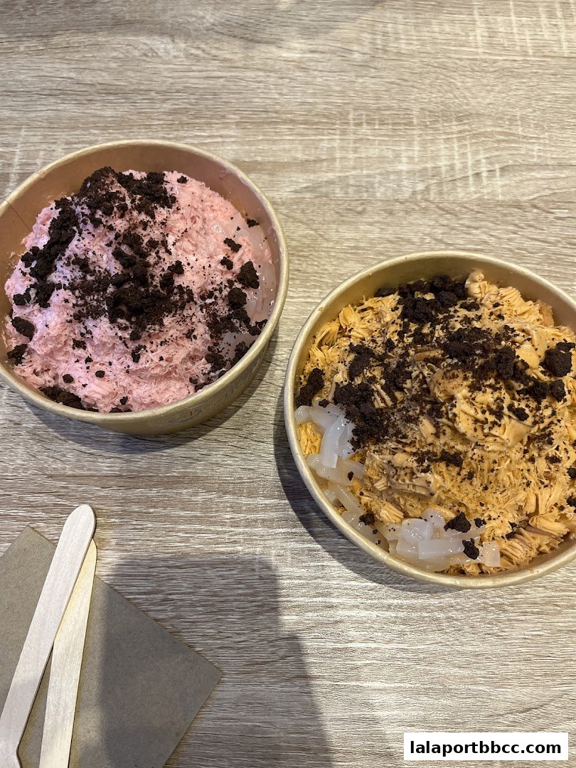 Two bowls of shaved ice desserts with toppings on a wooden table.