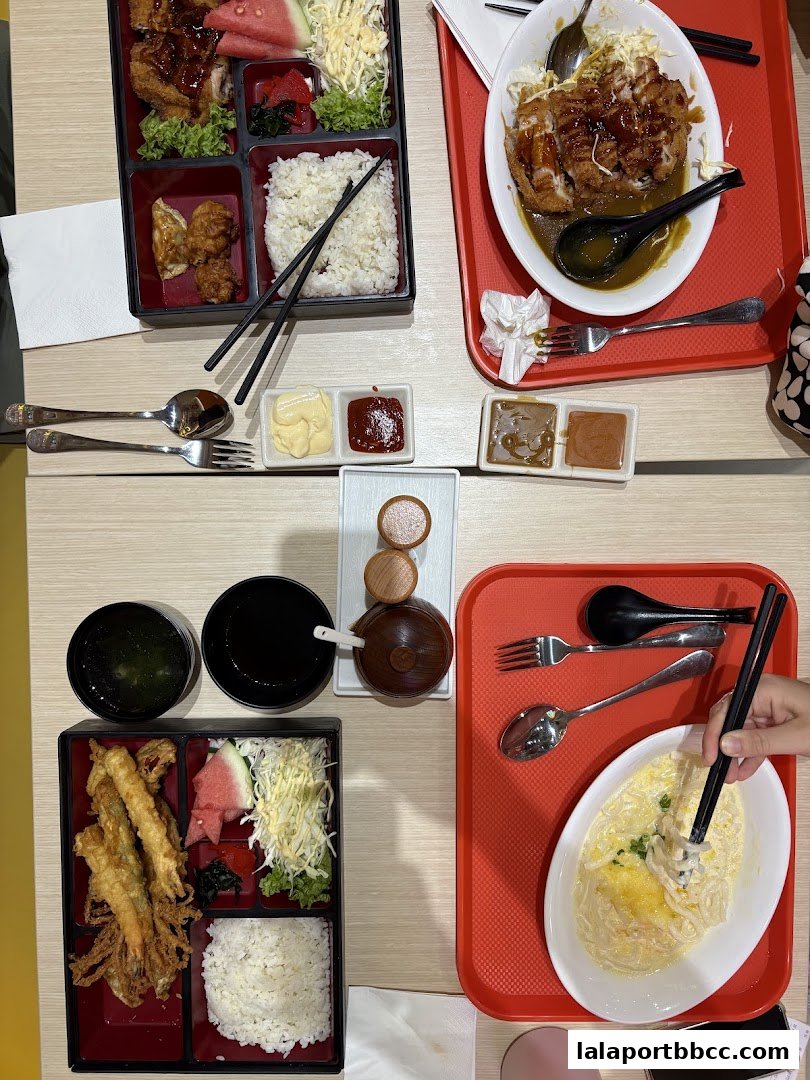 Two bento boxes and a bowl of curry rice are displayed on a table.