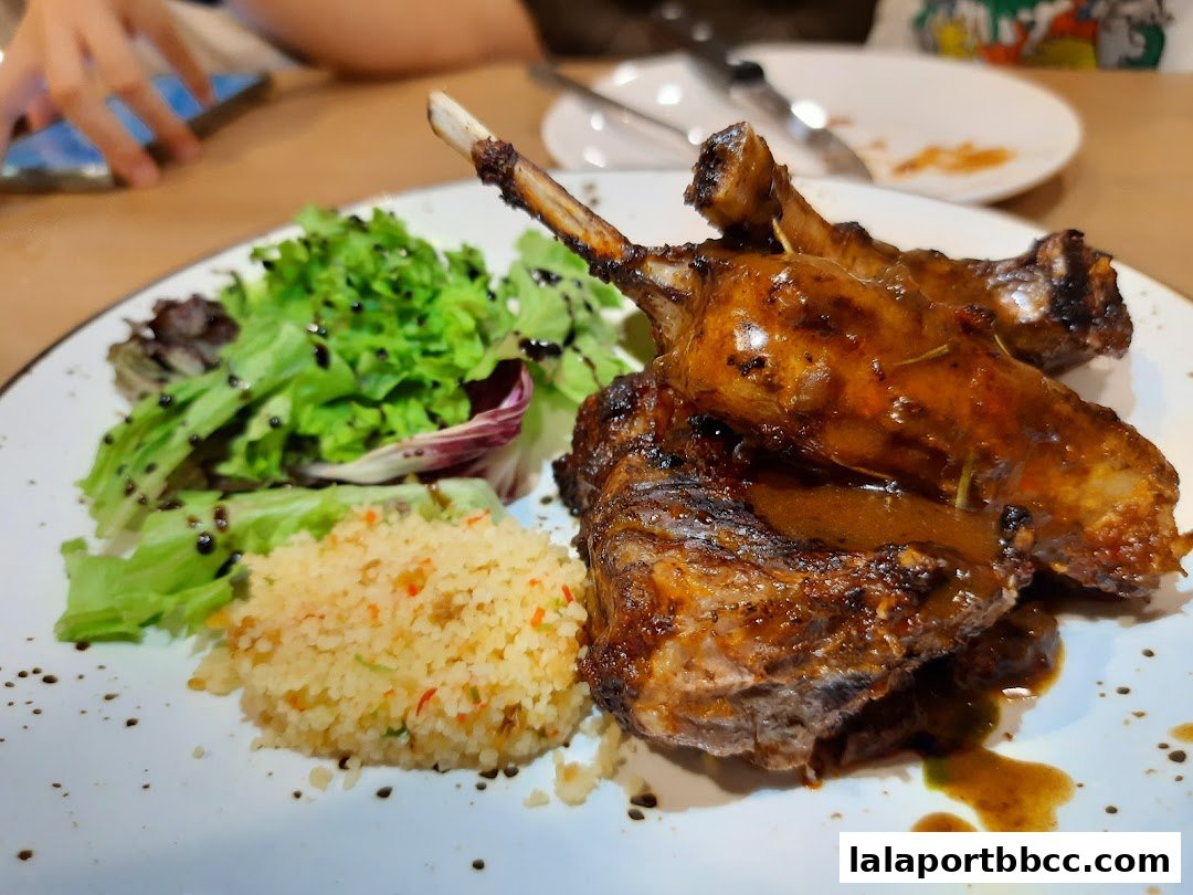 A plate of succulent lamb chops served with a fresh green salad and couscous.